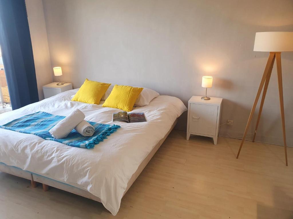 a white bed with yellow pillows and books on it at Vue sur Paris in Ivry-sur-Seine