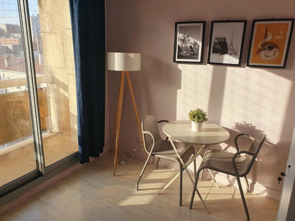 a dining room with a table and chairs and a floor lamp at Vue sur Paris in Ivry-sur-Seine