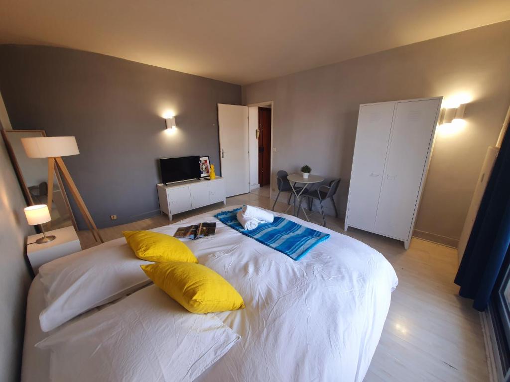 a bedroom with a large white bed with yellow pillows at Vue sur Paris in Ivry-sur-Seine