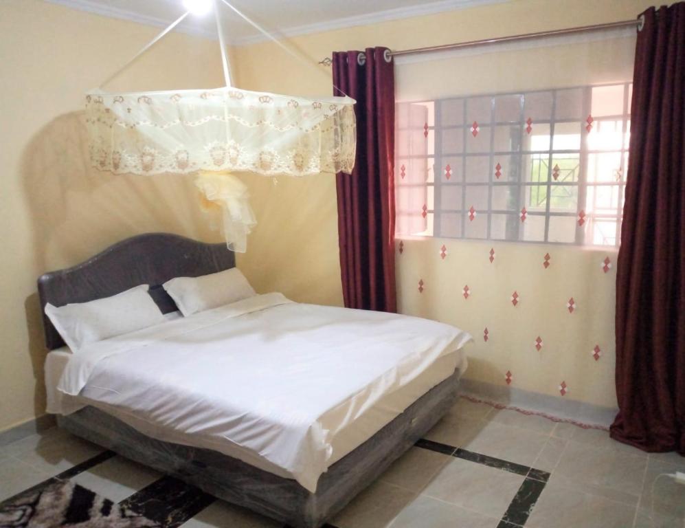 1 dormitorio con cama y lámpara de araña en Roma Stays - Budget Studio in Busia (Opp Shell petrol Station), en Busia