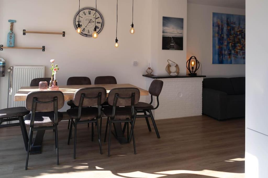 een eettafel met stoelen en een klok aan de muur bij 'Nieuw' Strand 83 - Family house in Egmond aan Zee