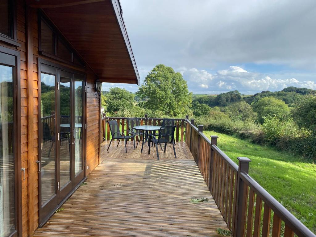 una terraza de madera con mesa y sillas. en Hazel Lodge luxury log cabin en South Wingfield