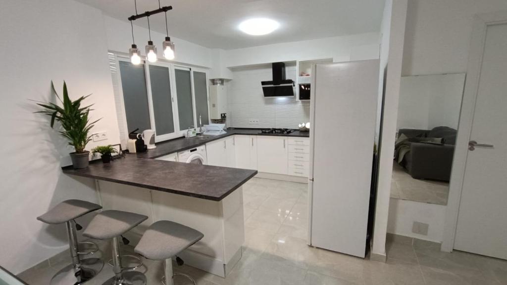 a white kitchen with a counter and stools in it at FUENGIROLA CENTRO in Fuengirola