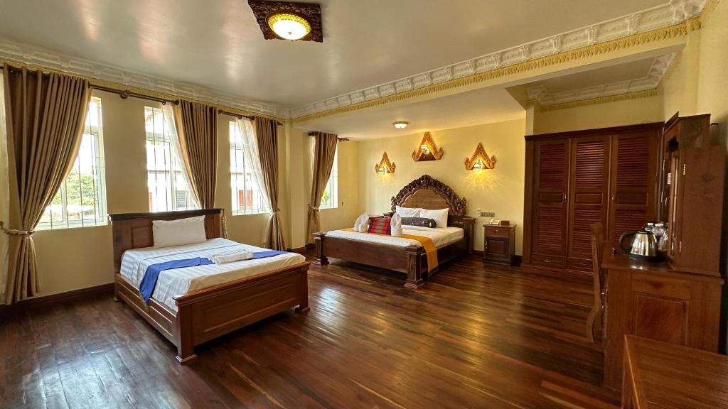 2 camas num quarto com pisos e janelas em madeira em OKAY Boutique Siem Reap em Phumĭ Ta Phŭl