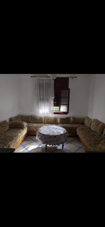 uma sala de estar com um sofá e uma mesa em Appartement à 8 mn de mehdia plage em Kenitra