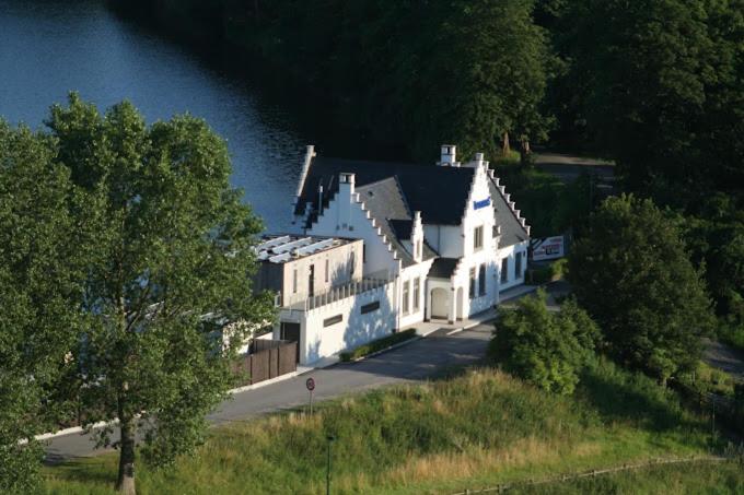 een groot wit huis op een heuvel naast een meer bij vakantiewoning het vijverhuis in Zillebeke