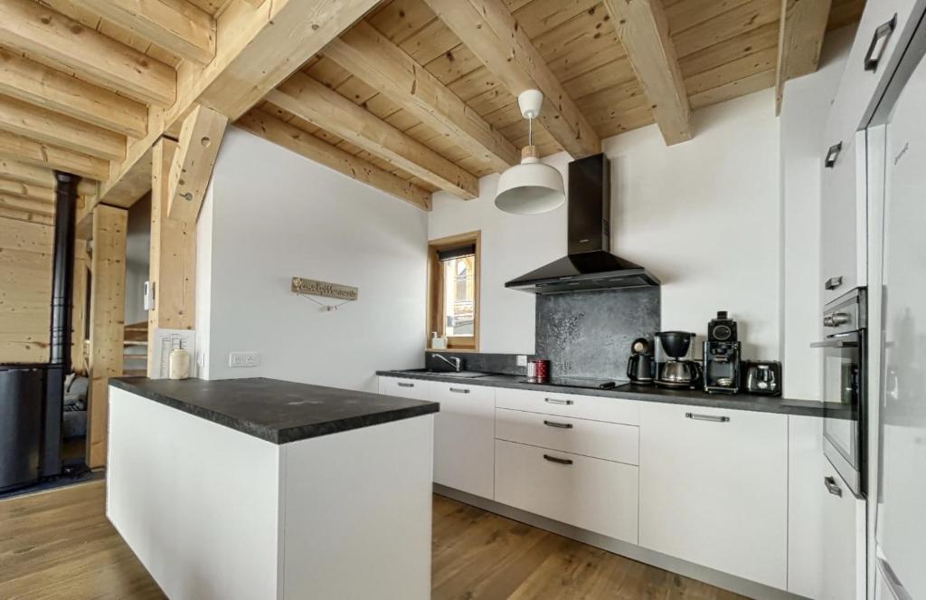 uma cozinha com armários brancos e um balcão preto em Chalet Le Clapière em La Toussuire