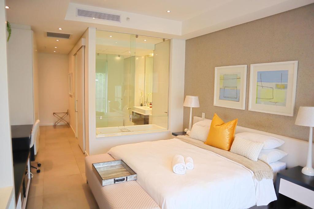 a bedroom with a large white bed and a bathroom at Love Luxe @ Sandton skye in Johannesburg