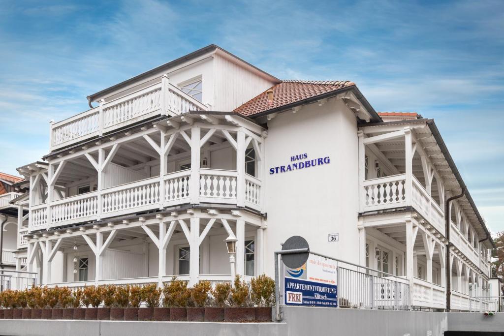 a white building with a sign on the side of it at Haus Strandburg - hinter Düne und Meer in Binz