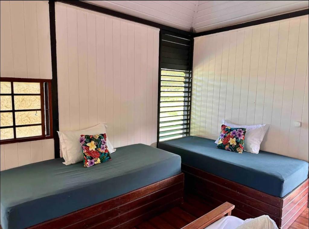 two beds in a room with two windows at Fare miti access private white sand beach in Moorea