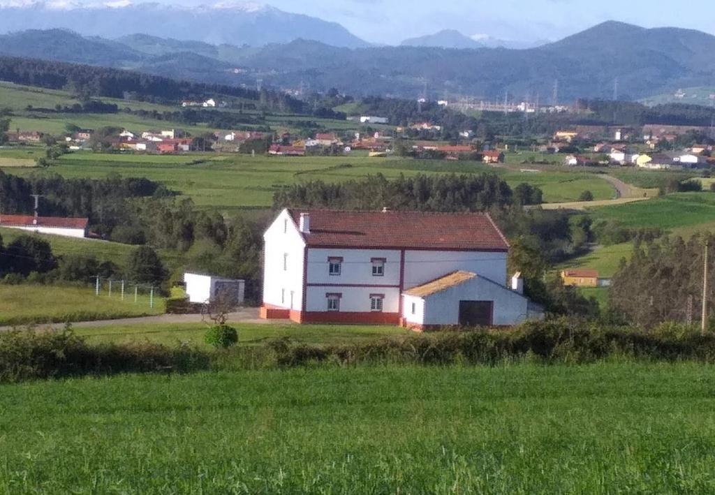una casa blanca en medio de un campo verde en Finca El Carbayal, en El Campo