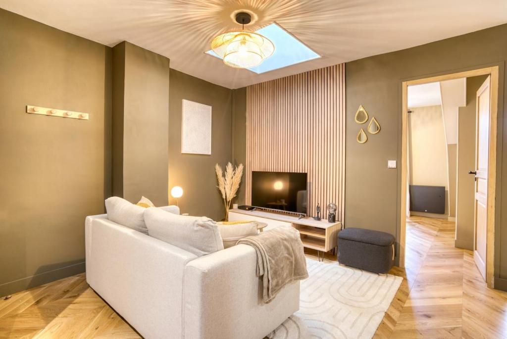 un salon avec un canapé blanc et une télévision dans l'établissement Le France - Les Jardins de Diane, à Fontainebleau