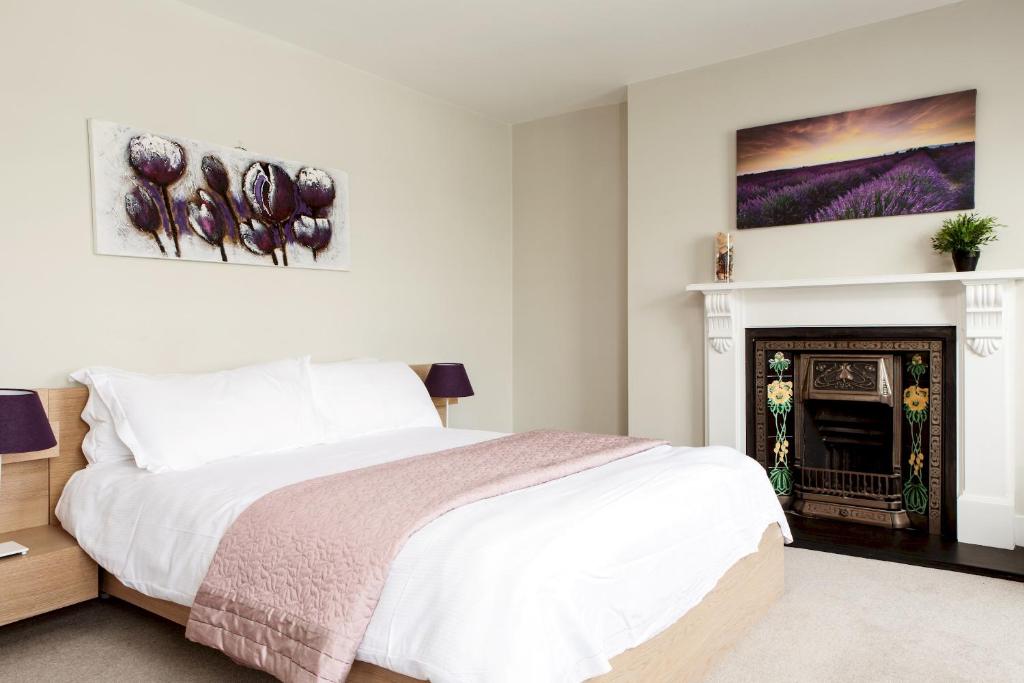 a white bedroom with a bed and a fireplace at Madison Hill - Fernlea View 4 - Two bedroom flat in London