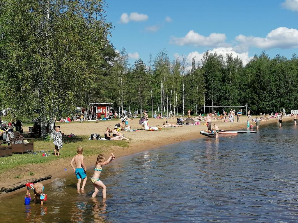 Emolahti Camping في Pyhäjärvi: مجموعة من الناس يلعبون في الماء على الشاطئ