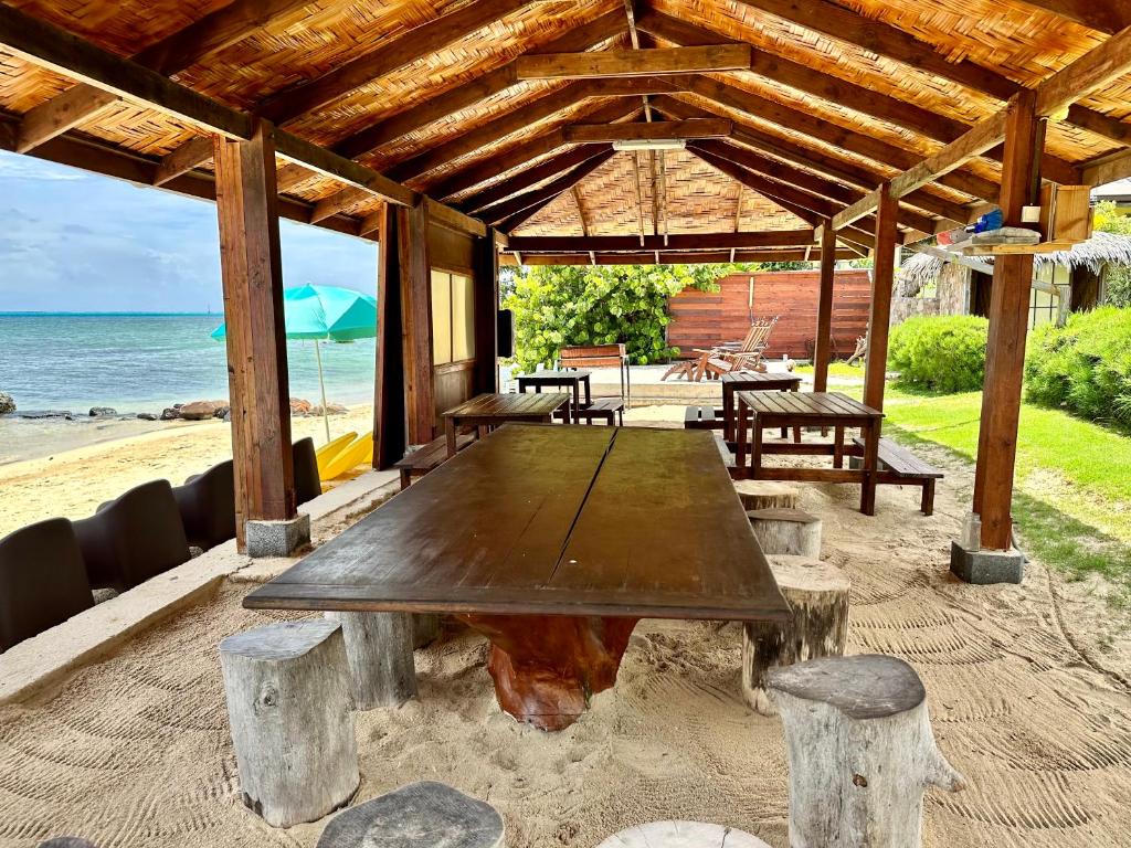 a wooden table sitting under a pavilion on the beach at Fare miti access private white sand beach in Moorea