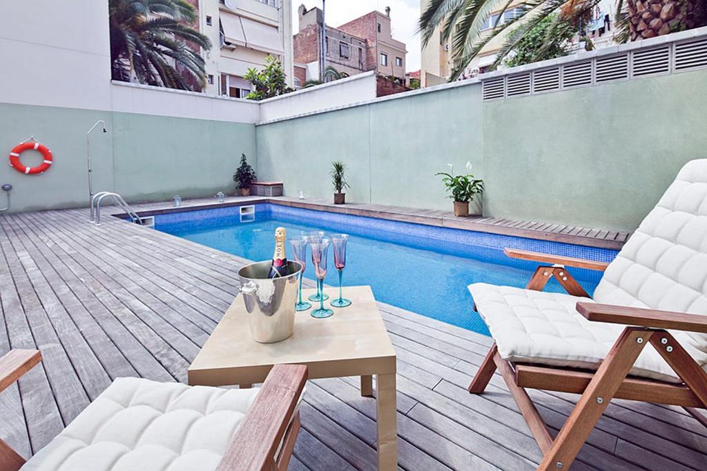 un patio con mesa, sillas y piscina en Barcino Inversions - Bright Apartment in Gracia with shared Pool en Barcelona