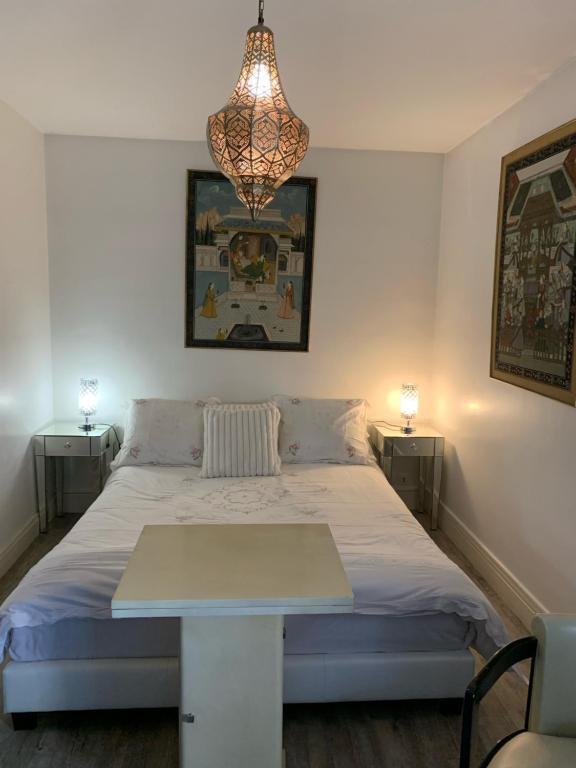 1 dormitorio con 1 cama con mesa y lámpara de araña en L'ELEGANCE SOUS LE SOLEIL, en Levallois-Perret