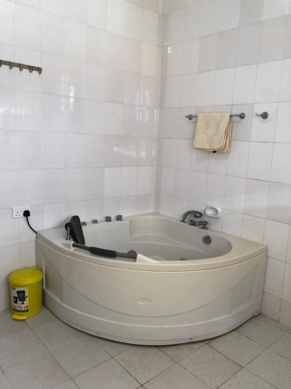 a white bath tub in a white tiled bathroom at Jambo hostel tz in Dar es Salaam