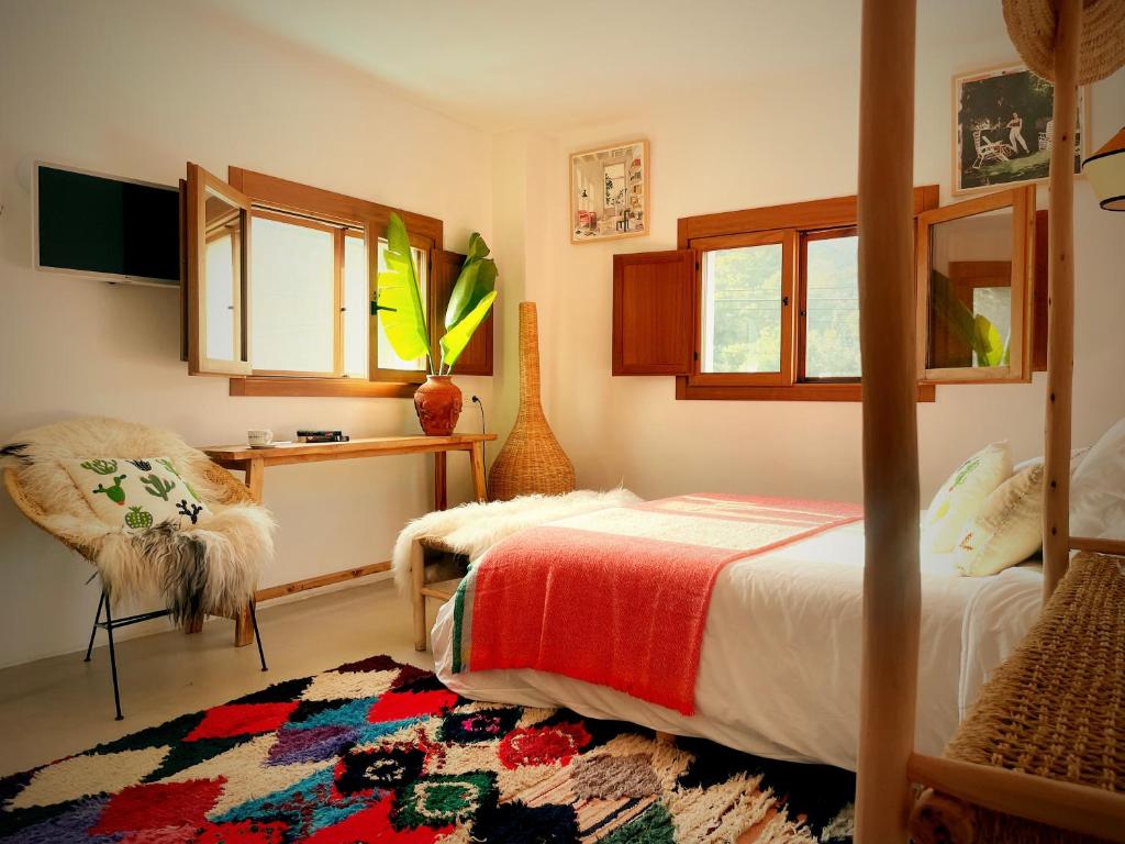 a bedroom with a bed and a chair and windows at Hostal Mar y Sal in Sant Josep de sa Talaia