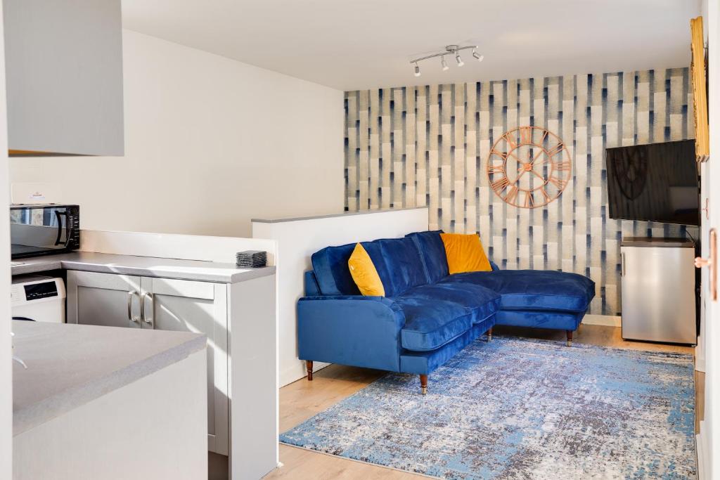 a living room with a blue couch and a kitchen at Little Edge: Bright and Modern Central Apartment in Berwick-Upon-Tweed