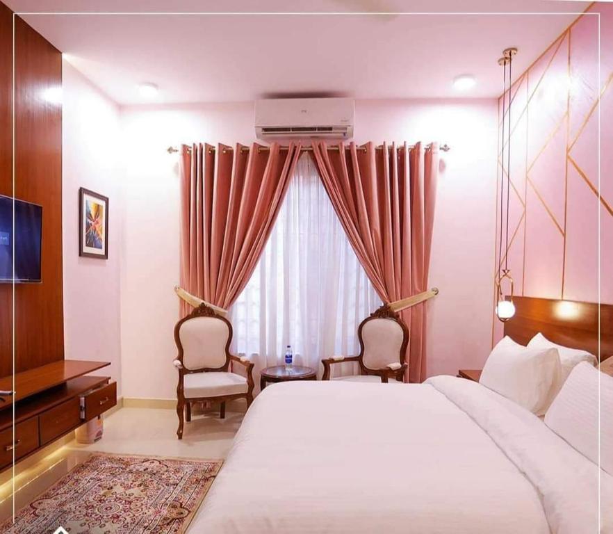 a bedroom with a bed and two chairs and a window at A One Hotel Clifton in Karachi
