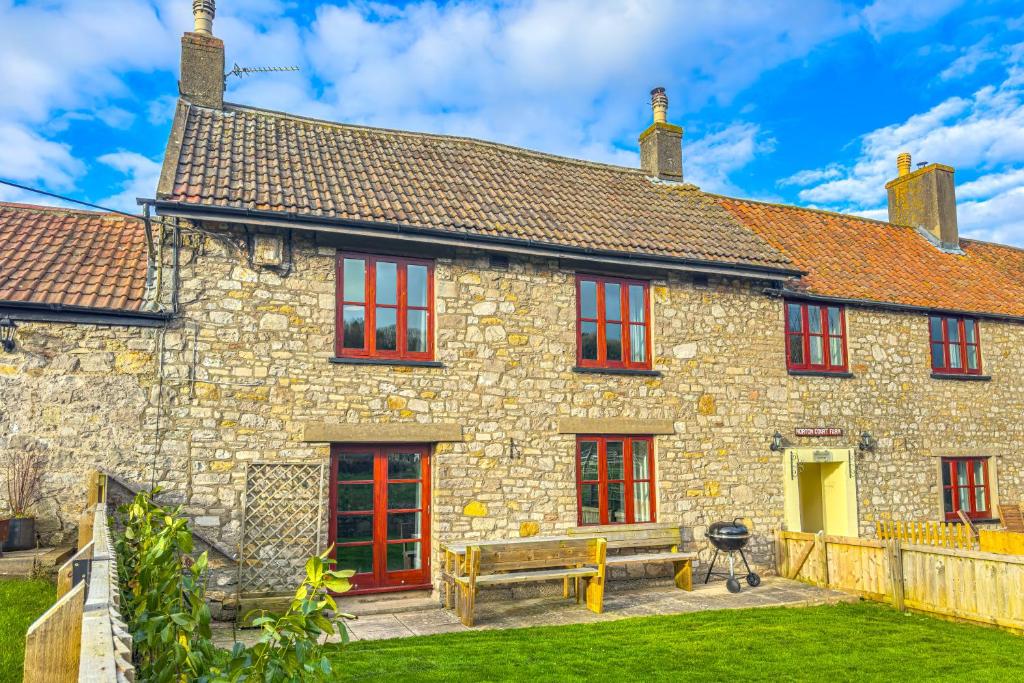 an old stone house with red windows and a bench at Spacious-Rustic Cottage-Dog Friendly-w log burner in Worle