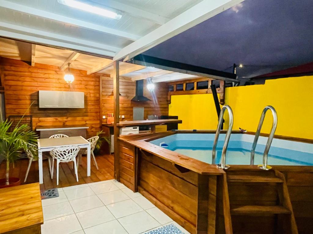 eine Whirlpool-Badewanne in einem Zimmer mit Tisch in der Unterkunft Myosotis, charmant logement central avec piscine privée, wifi et parking gratuit in Petit-Bourg
