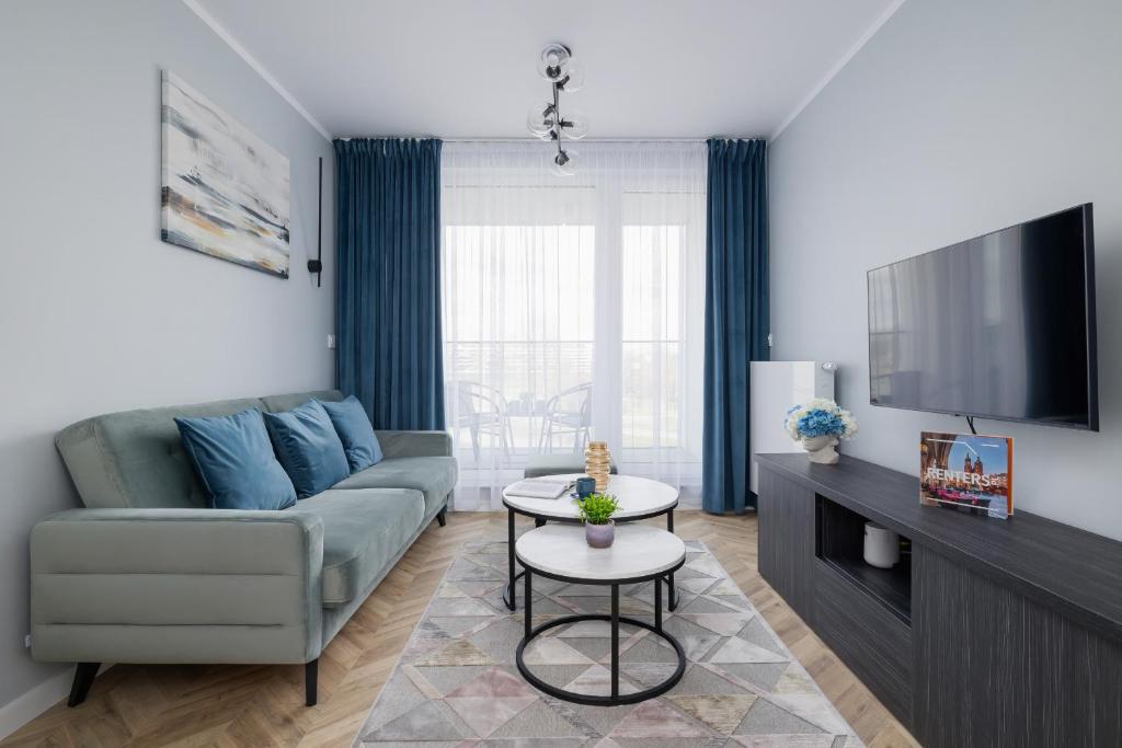 uma sala de estar com um sofá e uma televisão em Unique Apartment with Balcony & Parking Zabłocie Cracow by Renters Prestige em Cracóvia