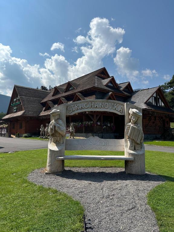 un banco de piedra frente a un edificio en Hotel Strachanovka - Jánska Koliba, en Liptovský Ján