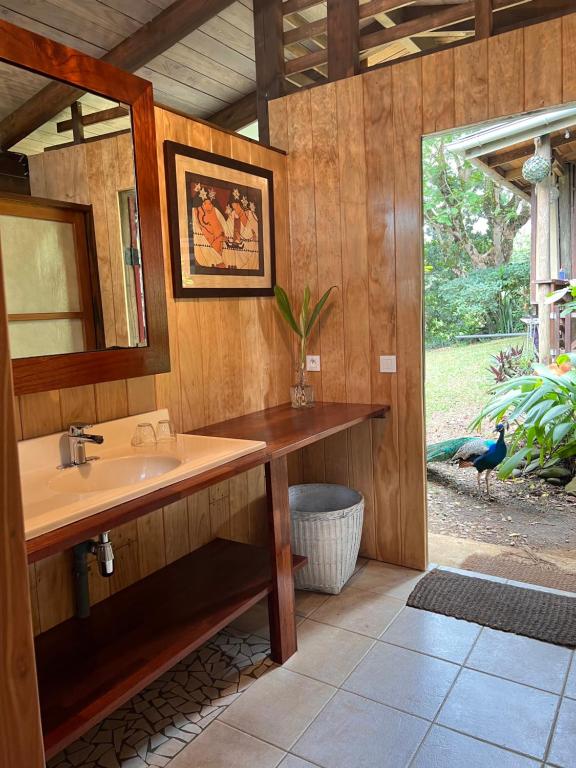 ein Badezimmer mit einem Waschbecken und einem Vogel, der draußen steht in der Unterkunft My Mountain Home in Taravao
