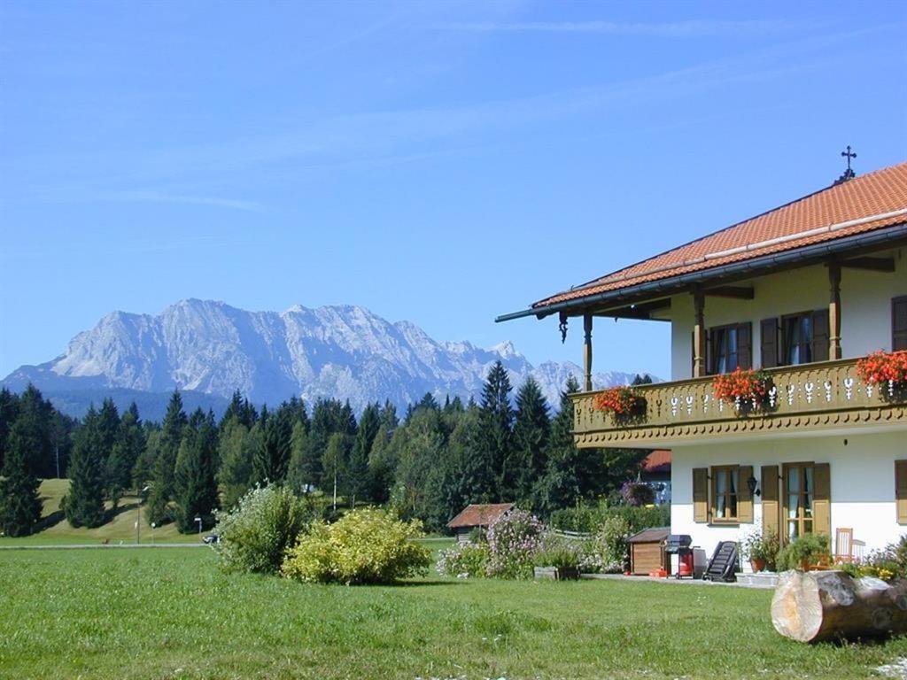 uma casa num campo com montanhas ao fundo em Ferienwohnungen Zum Baur em Krün