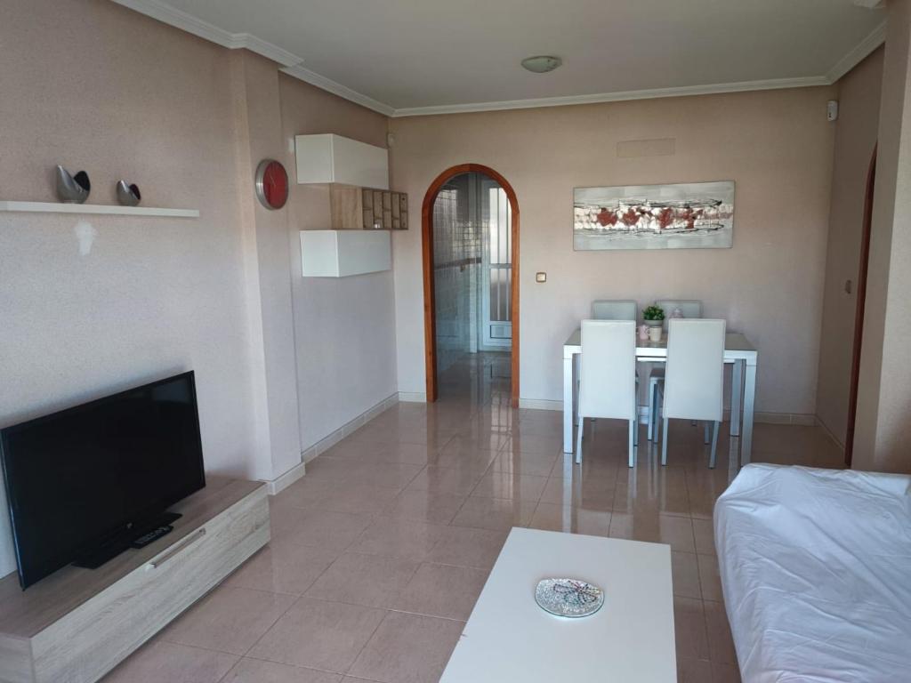 een woonkamer met een televisie en een eetkamer bij APARTAMENTO ZENIA PLAYA GOLF II in Alicante