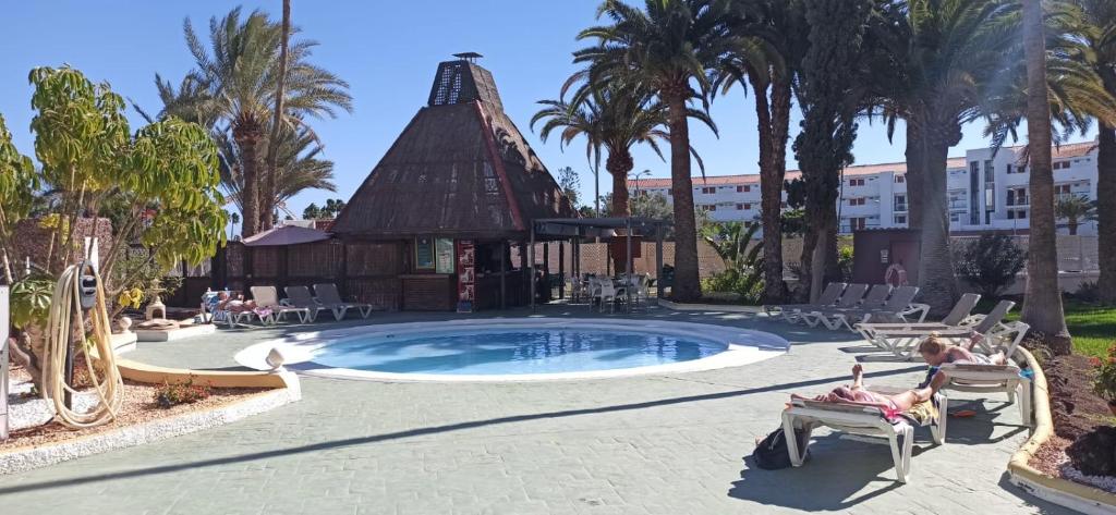 a resort with a pool and a building with palm trees at Paraíso Maspalomas Experience in San Bartolomé
