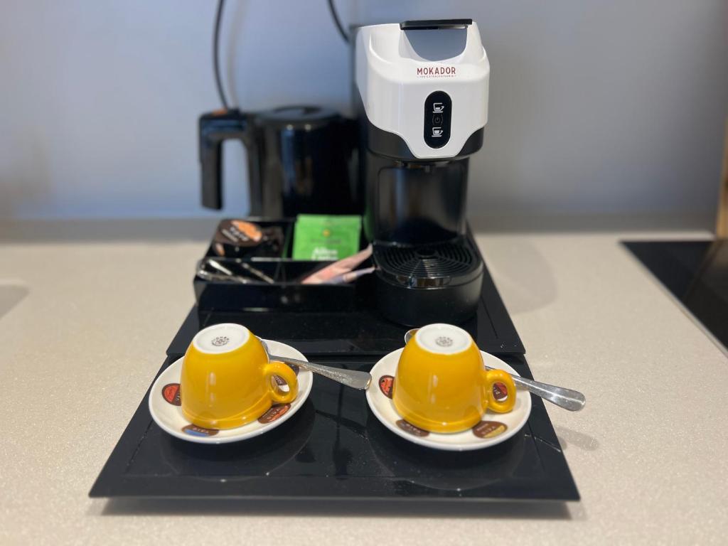 two yellow coffee cups on a counter with a coffee maker at Pakat Residences in Vienna
