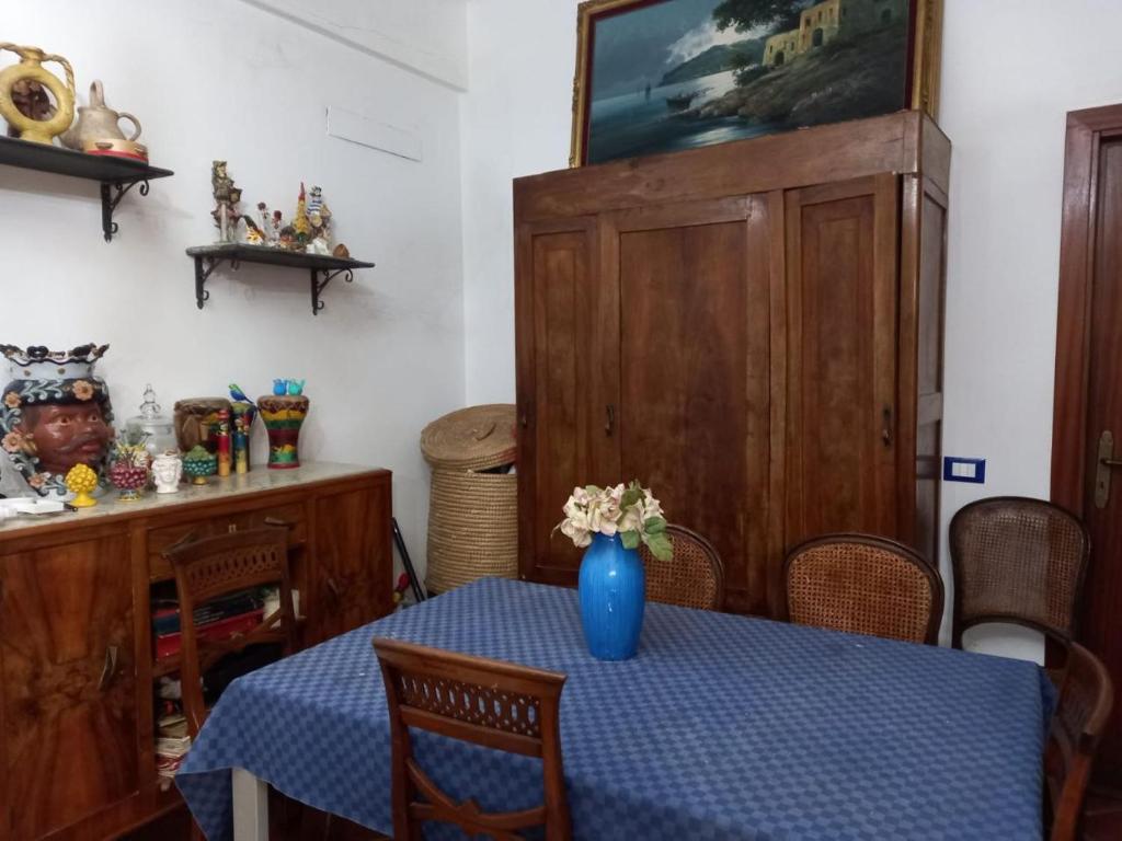 einen Esstisch mit einer blauen Vase mit Blumen darauf in der Unterkunft Villa Maruzza (Sicilia Bedda) in Carini