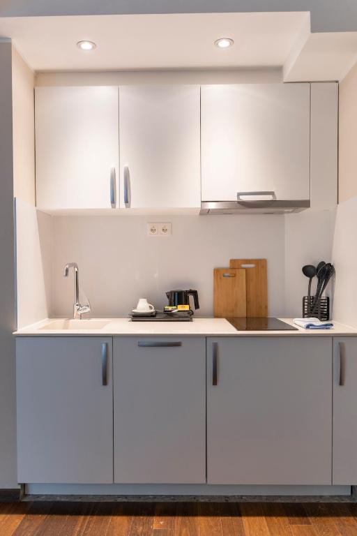 a kitchen with white cabinets and a sink at Pakat Residences in Vienna