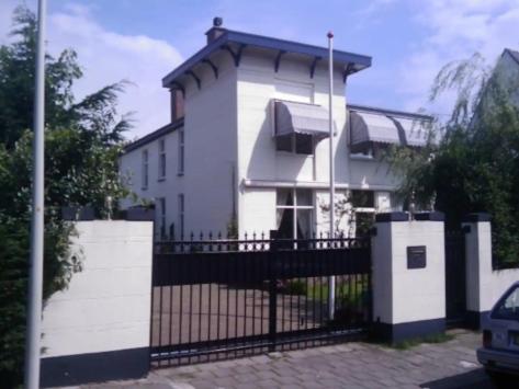 una casa blanca con una puerta y una valla en Villa Insulinde en Scheveningen