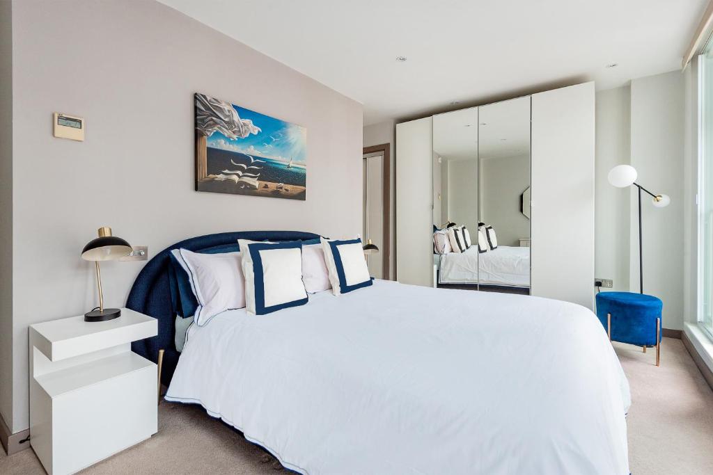 Arcore Premium Apartments: Mayfair في لندن: غرفة نوم بسرير ابيض وكرسي ازرق