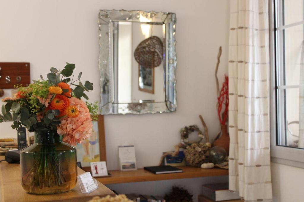 un jarrón de flores sobre una mesa con un espejo en Hôtel Restaurant Petra Cinta, en Barcaggio