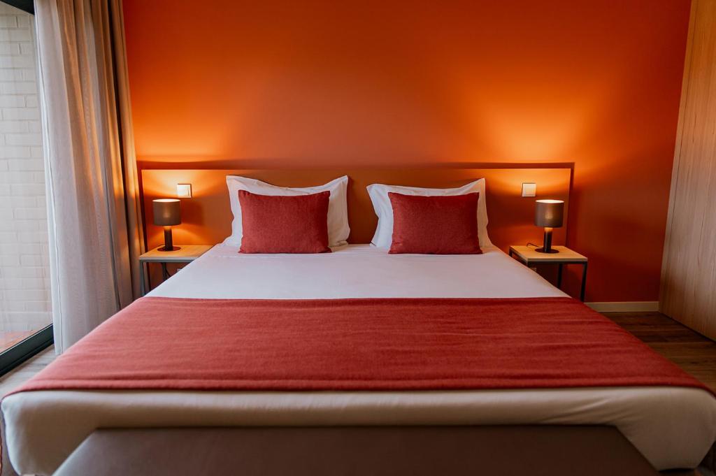 a bedroom with a large bed with two red pillows at Meu Hotel Porto Gandra in Paredes