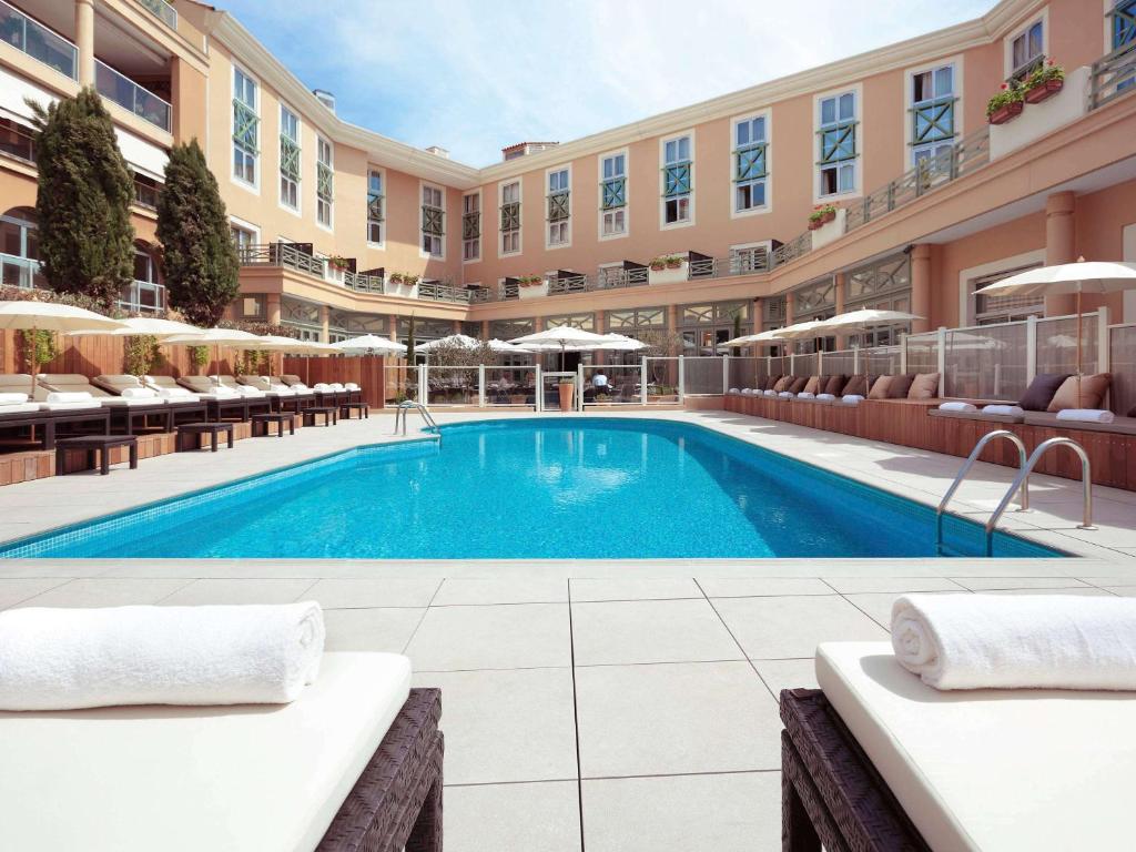 una piscina en un hotel con sillas y un edificio en Grand Hôtel Roi René Aix en Provence Centre - MGallery en Aix-en-Provence