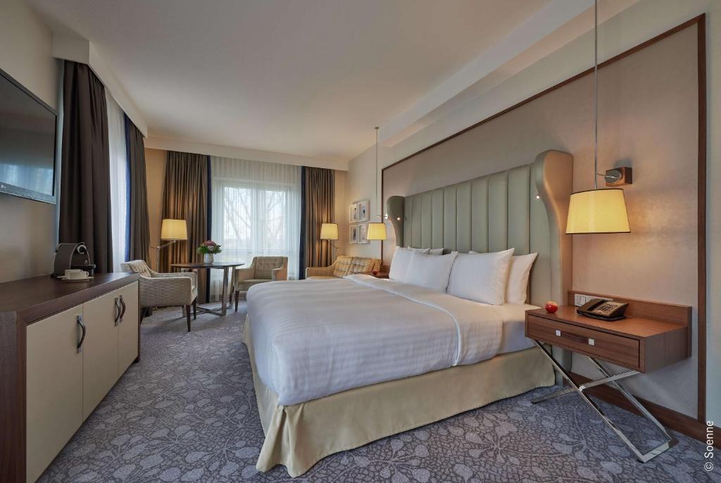 a hotel room with a large bed and a desk at Dorint Hotel Bonn in Bonn