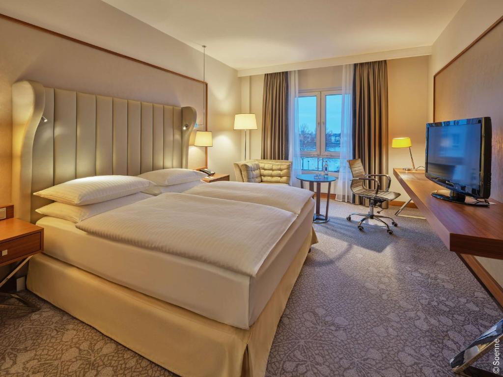 a hotel room with a large bed and a television at Dorint Hotel Bonn in Bonn