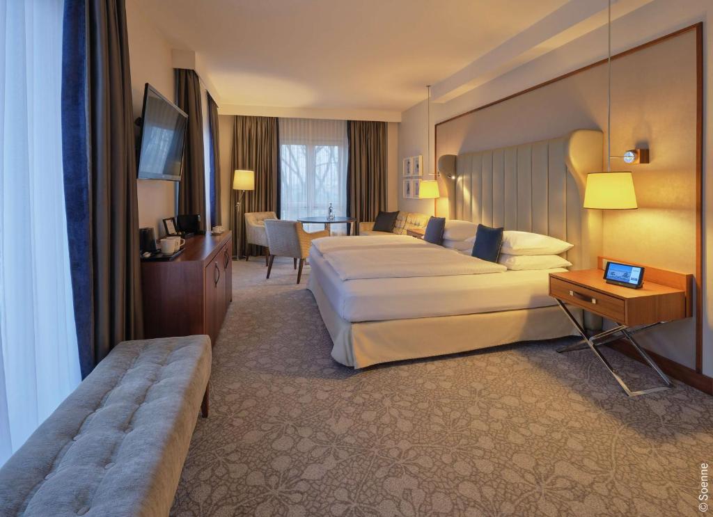 a hotel room with a large bed and a table at Dorint Hotel Bonn in Bonn