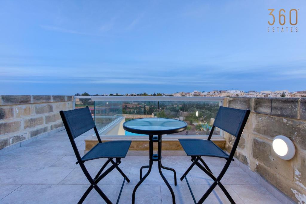 een tafel en 2 stoelen op een balkon met uitzicht bij LUX Villa with Private Pool, BBQ & Rooftop Oasis by 360 Estates in Kalkara