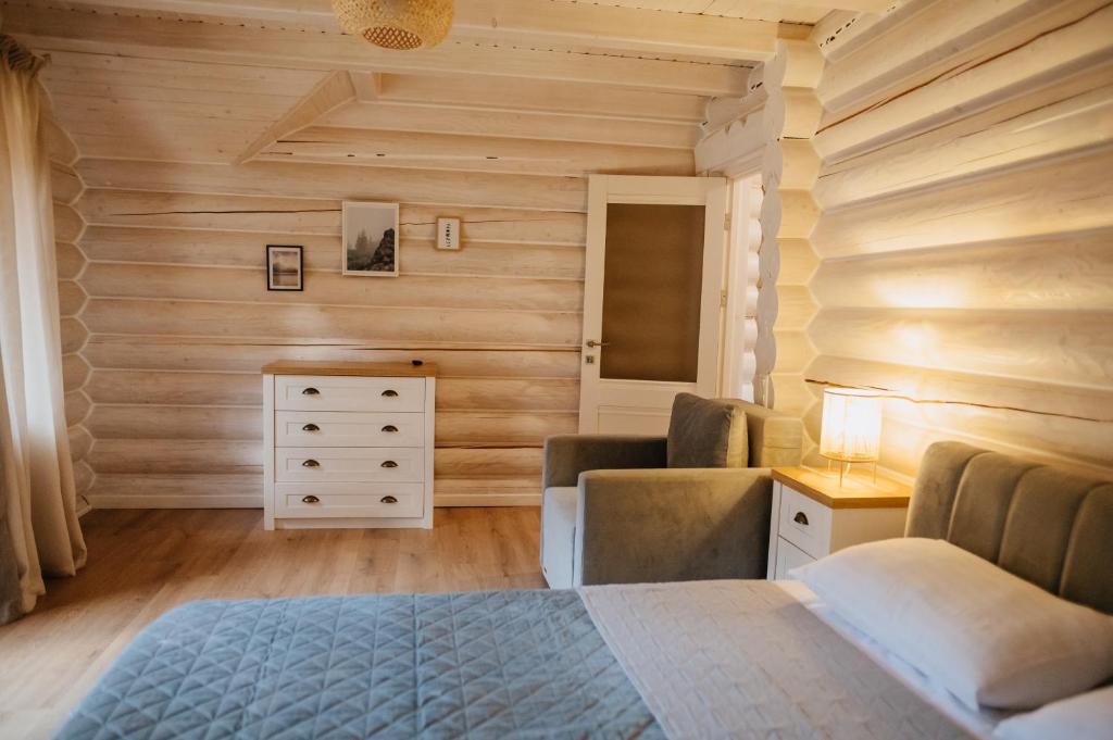 Schlafzimmer mit Holzwänden, einem Bett und einer Kommode in der Unterkunft Vila Mila in Mykulytschyn