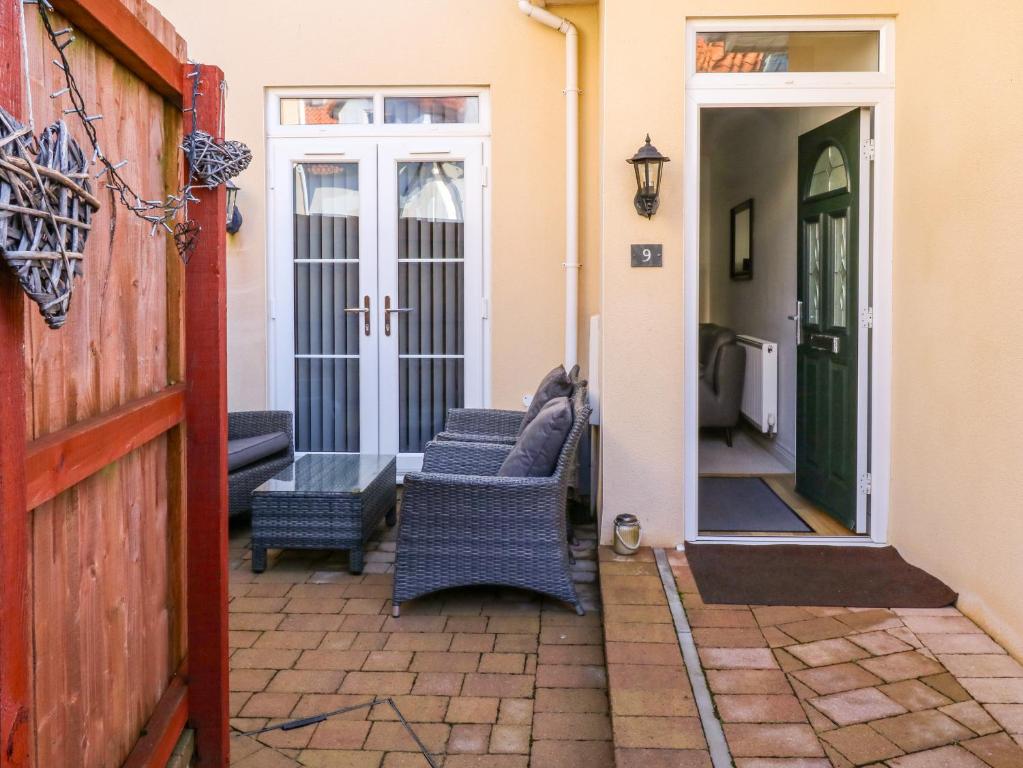 a patio with wicker chairs and a door to a house at 9 Seaford Sands in Paignton