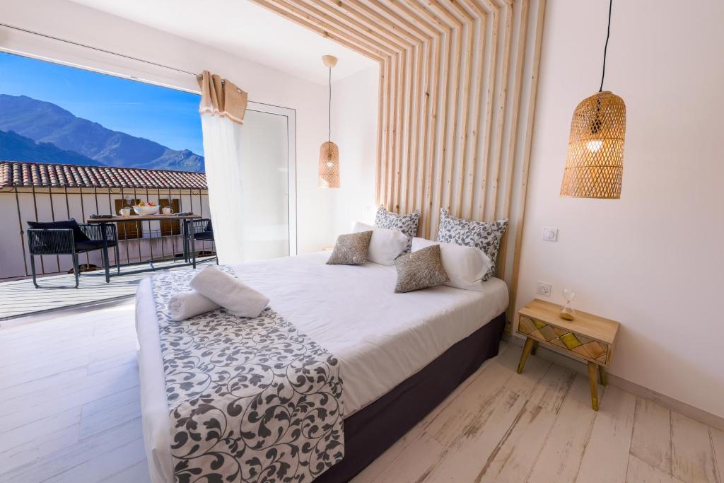 - une chambre avec un lit et un balcon avec une table dans l'établissement La Manufacture D'oriano LES NUITS AU VILLAGE, à Montegrosso