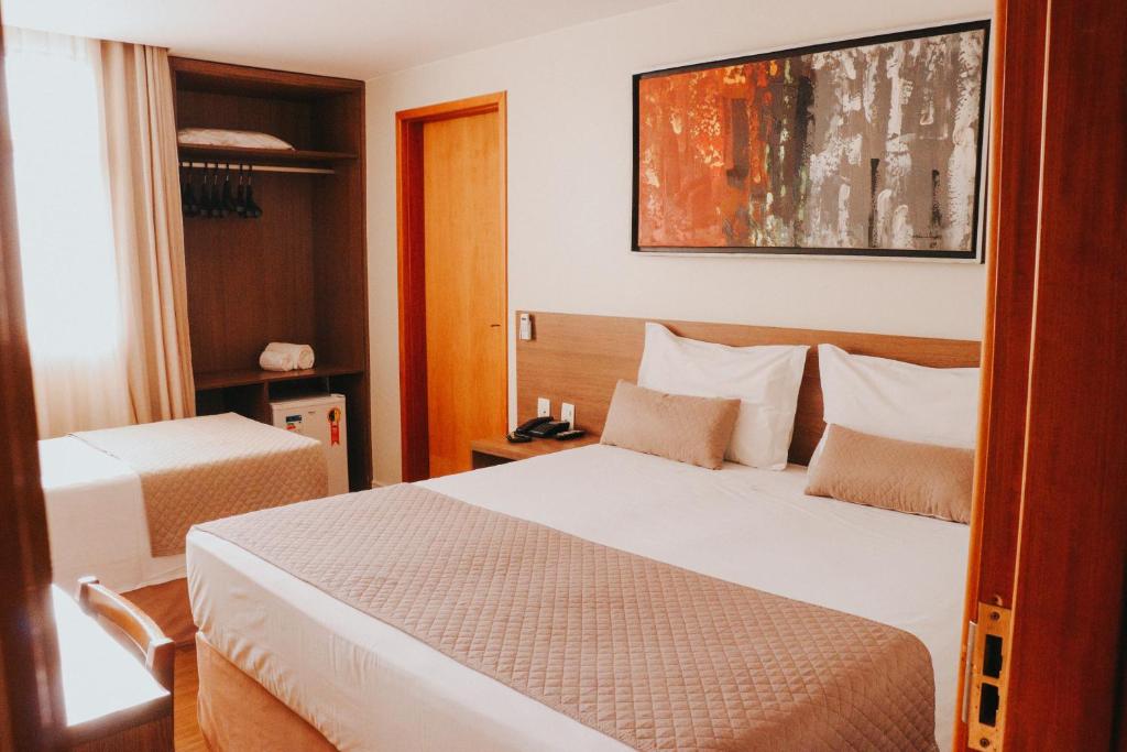 a hotel room with two beds and a picture on the wall at Vida Plaza Hotel in Brasília