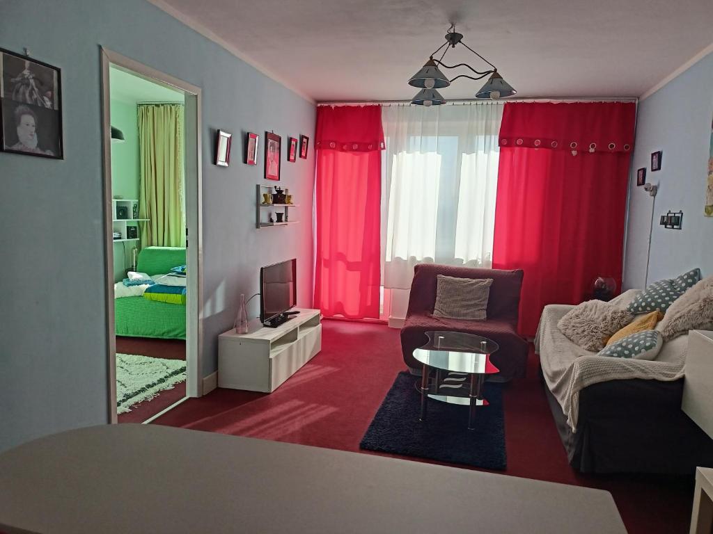 sala de estar con cortinas rojas y sofá en - PANORAMA -, en Sopot